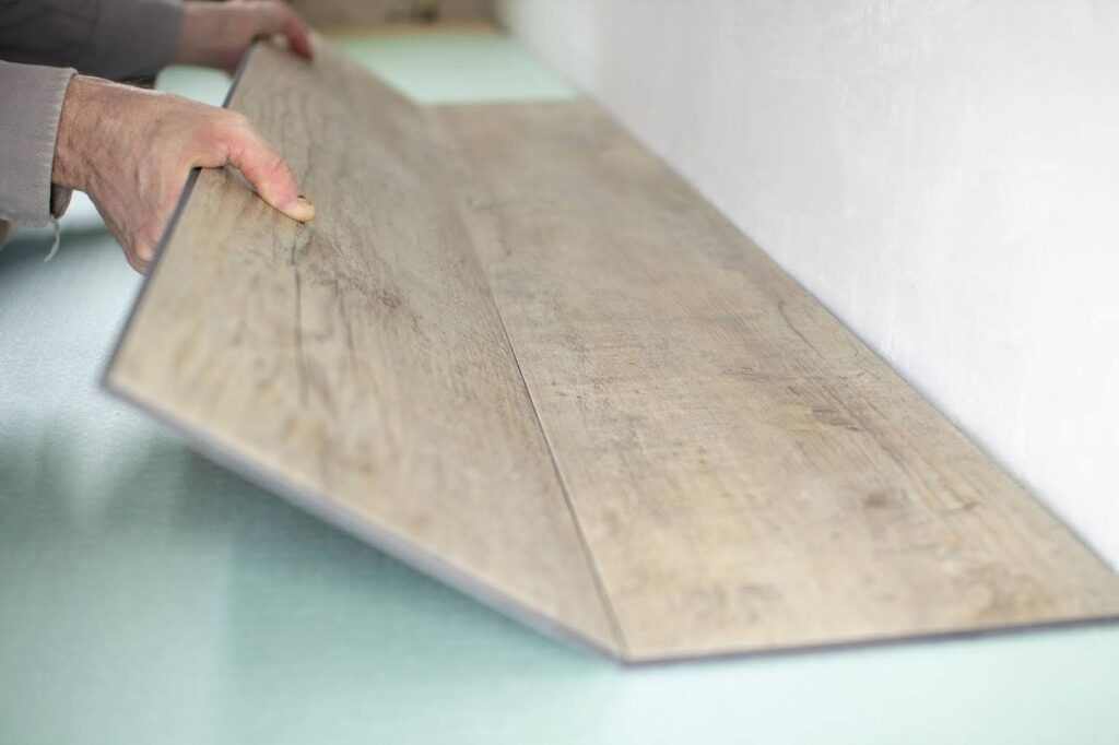 Man holding a vinyl plank floor panel.