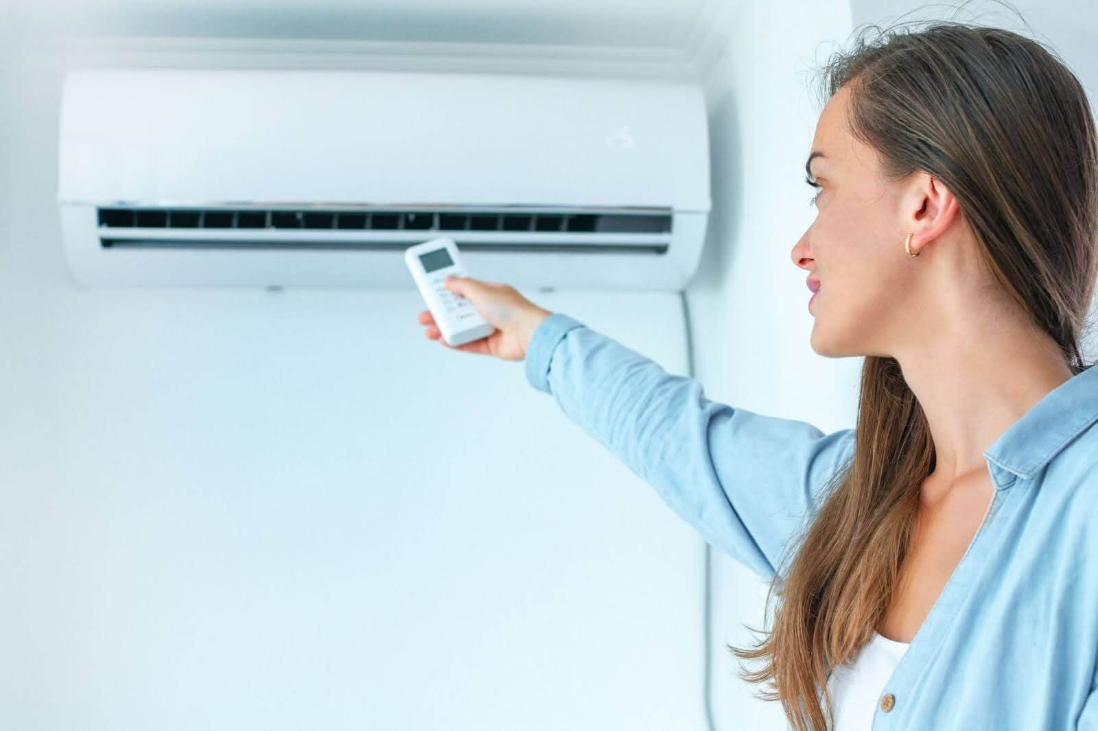 Woman turning on air conditioning.